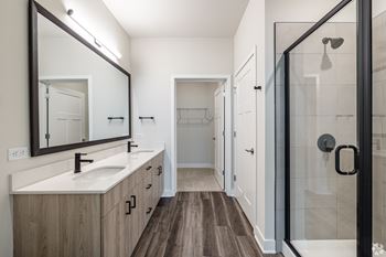 A bathroom with a sink, mirror, and shower.